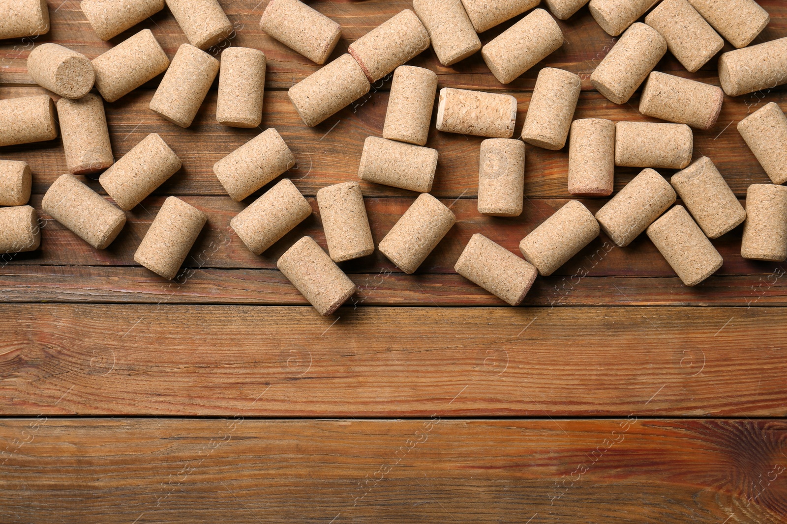 Photo of Many corks of wine bottles on wooden table, flat lay. Space for text