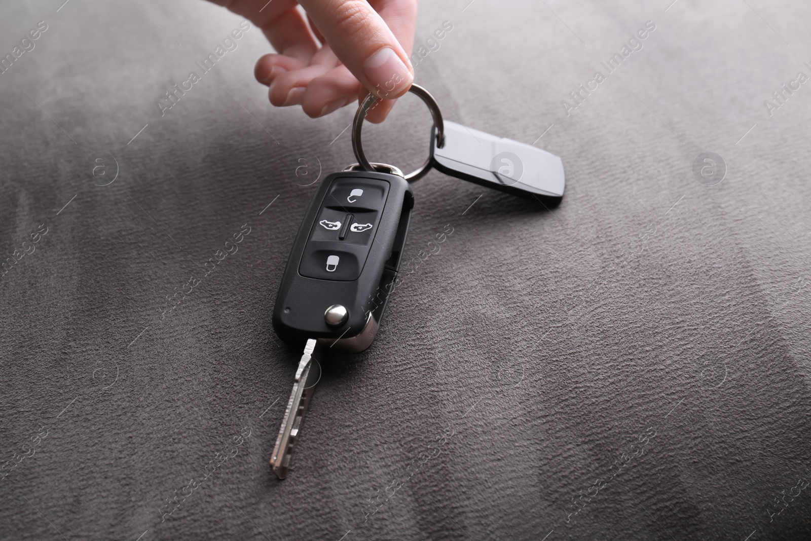 Woman holding car flip key on grey background, closeup Photo of Woman holding car flip key on grey background, closeup