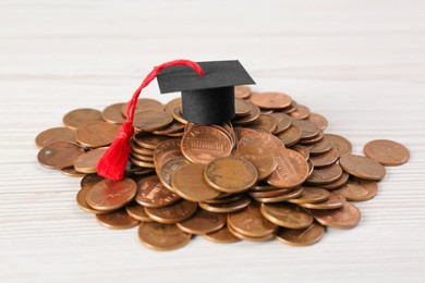 Photo of Scholarship concept. Graduation cap and coins on white wooden table