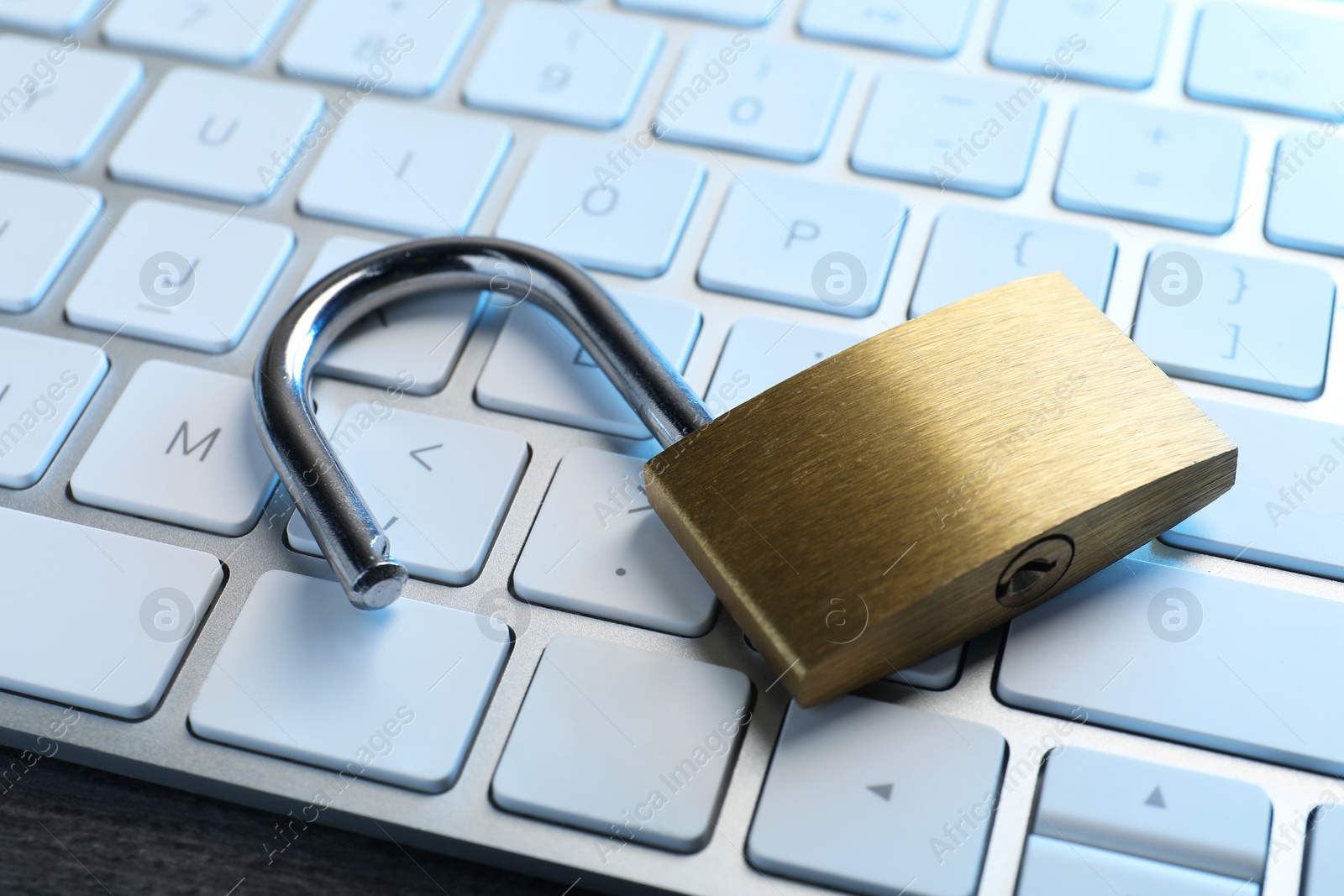 Photo of Cyber security. Open padlock and keyboard on table, closeup