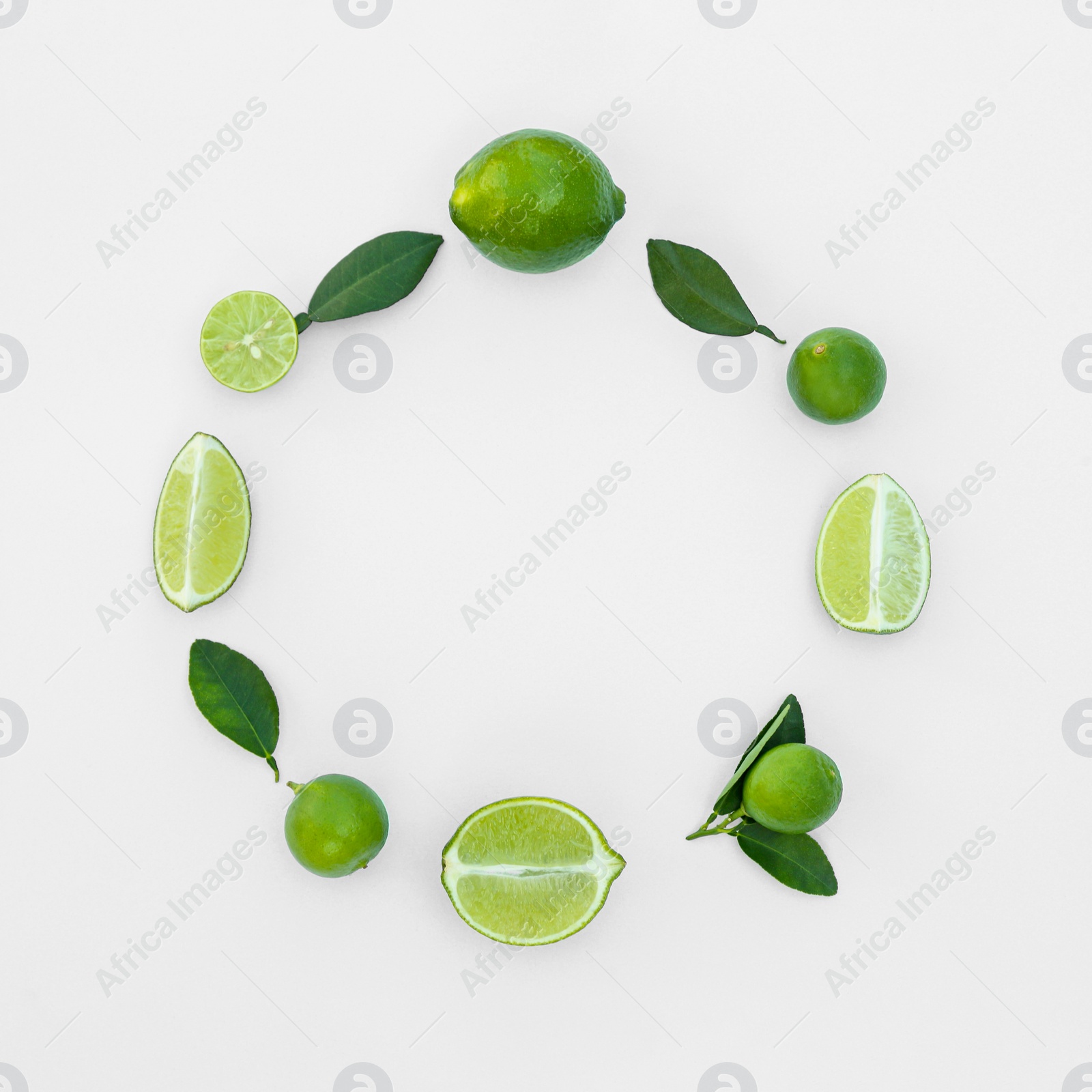 Photo of Frame made of fresh ripe limes and green leaves on white background, flat lay. Space for text