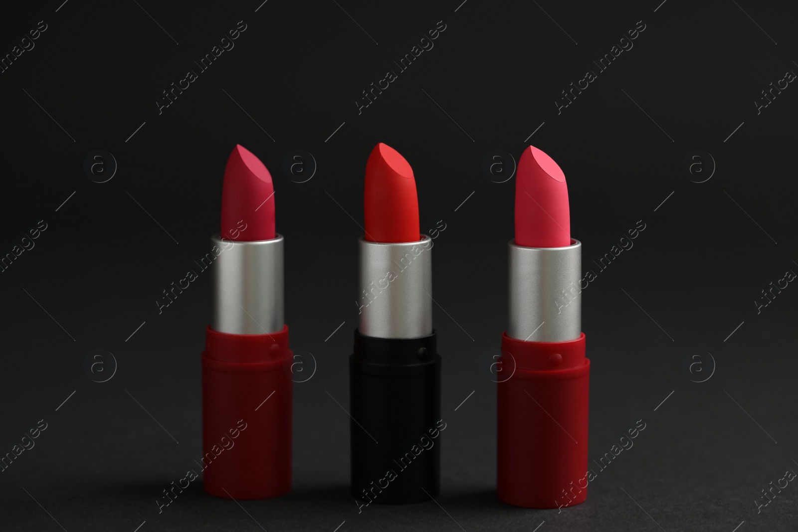 Photo of Different lipsticks on black background. Cosmetic product