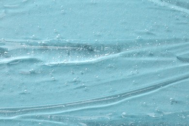 Photo of Clear cosmetic serum on light blue background, macro view