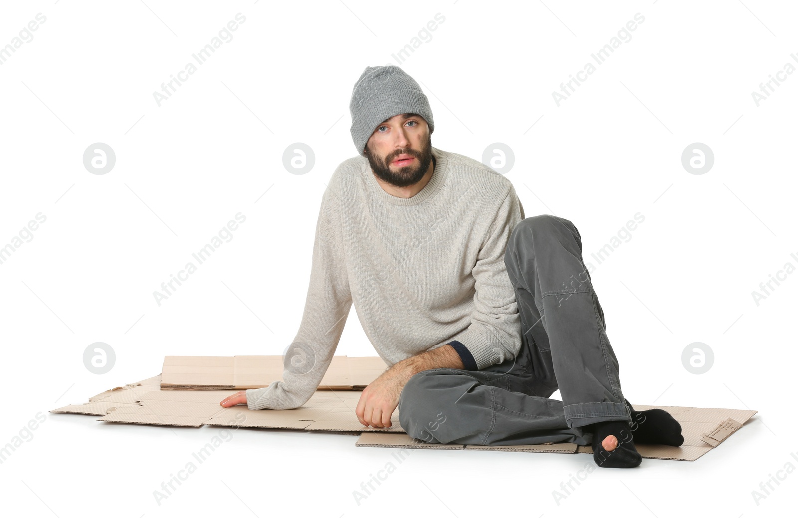 Photo of Poor homeless man sitting on cardboard, white background
