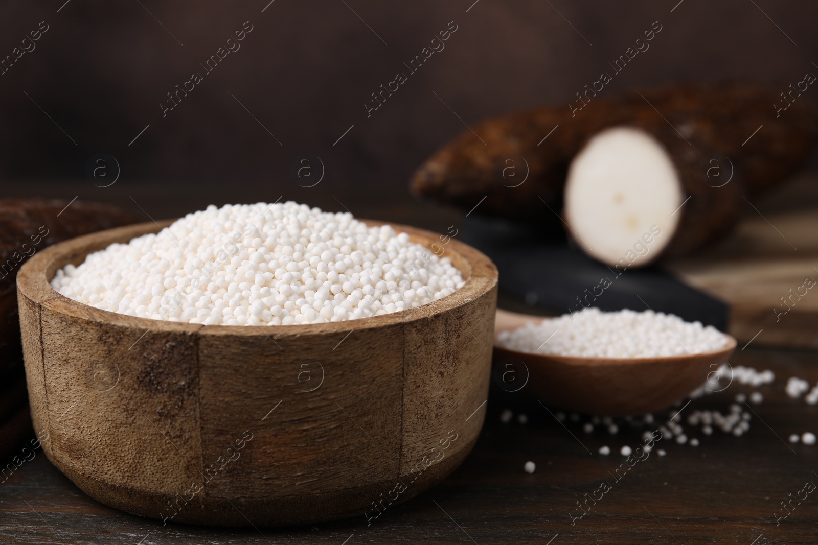 Photo of Bowl and spoon with tapioca pearls on wooden table, closeup