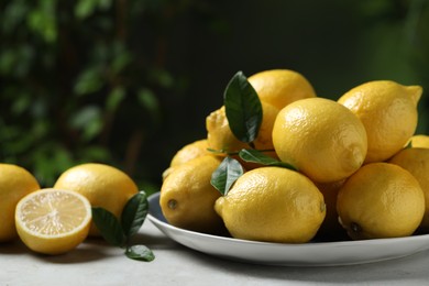 Photo of Fresh lemons and green leaves on table outdoors