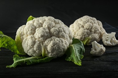 Photo of Fresh whole cauliflowers on black wooden table