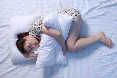 Photo of Young woman with pillow suffering from insomnia on bed, top view