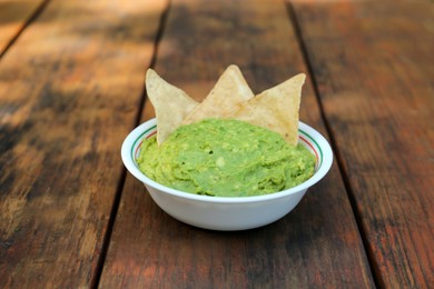 Delicious guacamole made of avocados with nachos on wooden table