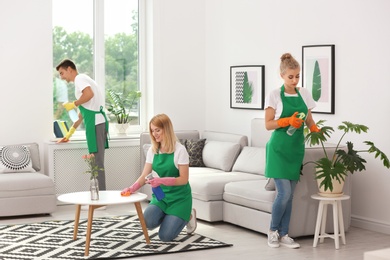 Team of professional janitors in uniform cleaning living room