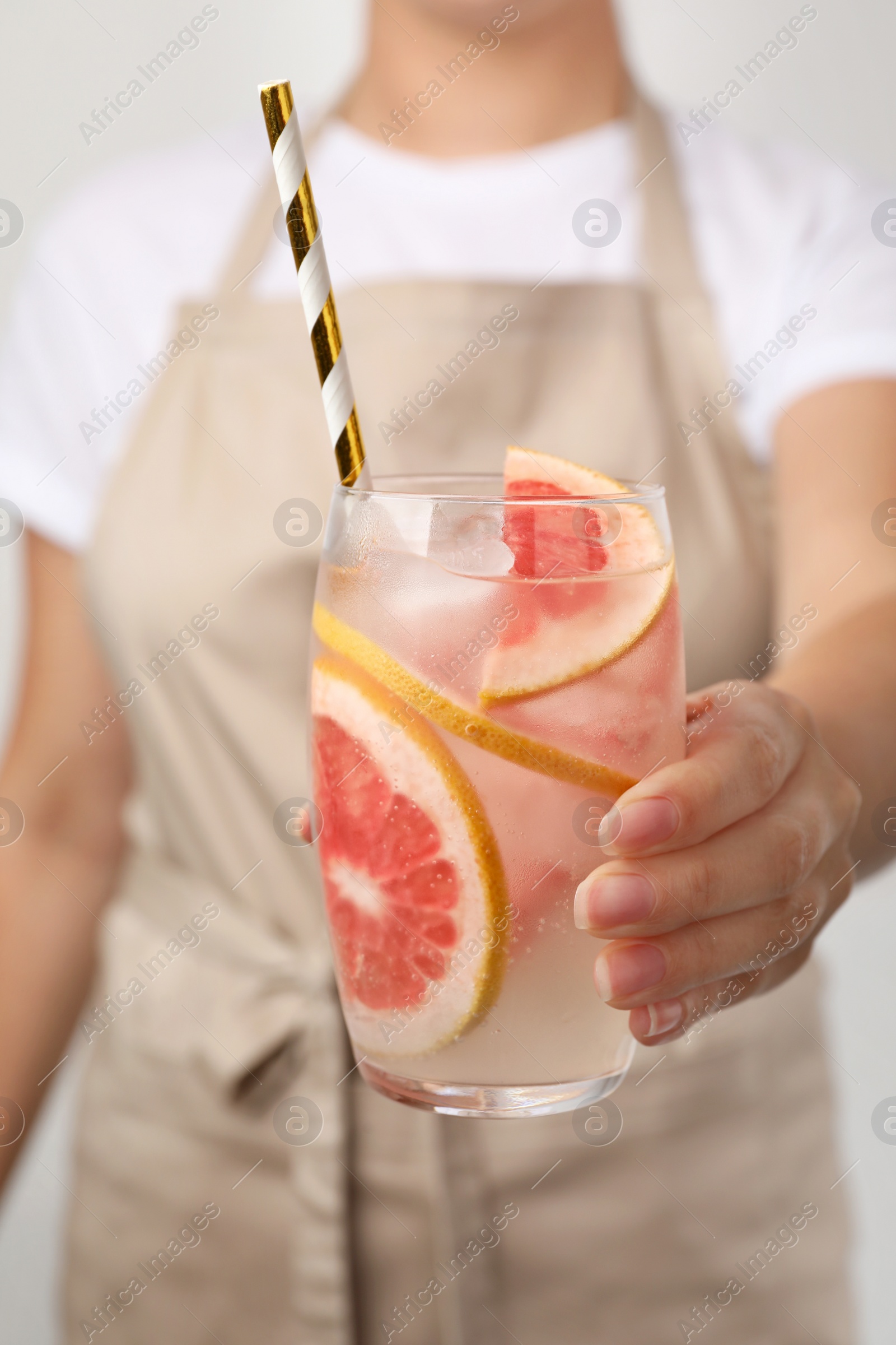 Photo of Woman holding glass of grapefruit refreshing drink with straw, closeup