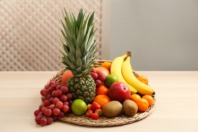 Wicker mat with different fresh fruits on wooden table