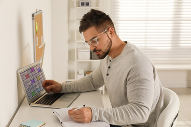 Young man using calendar app on laptop in office