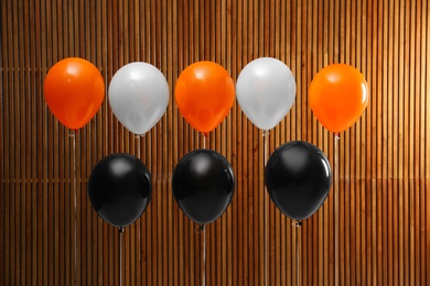 Photo of Colorful balloons against wooden wall. Halloween party