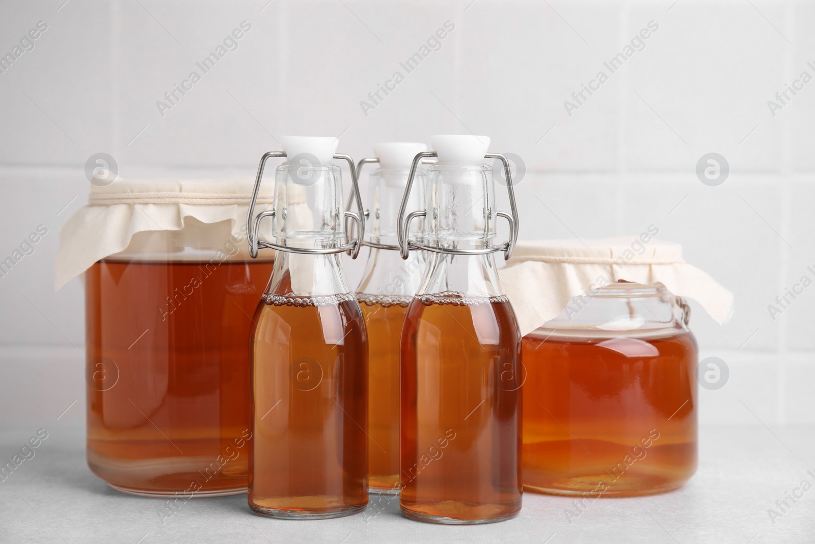 Photo of Tasty kombucha in glass jars and bottles on white table