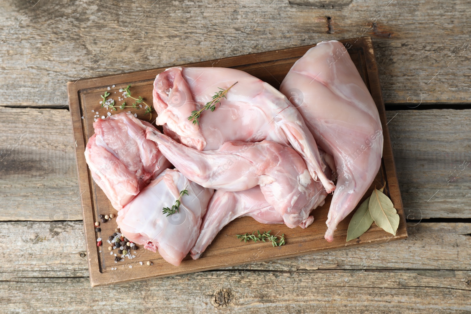 Photo of Fresh raw rabbit meat and spices on wooden table, top view