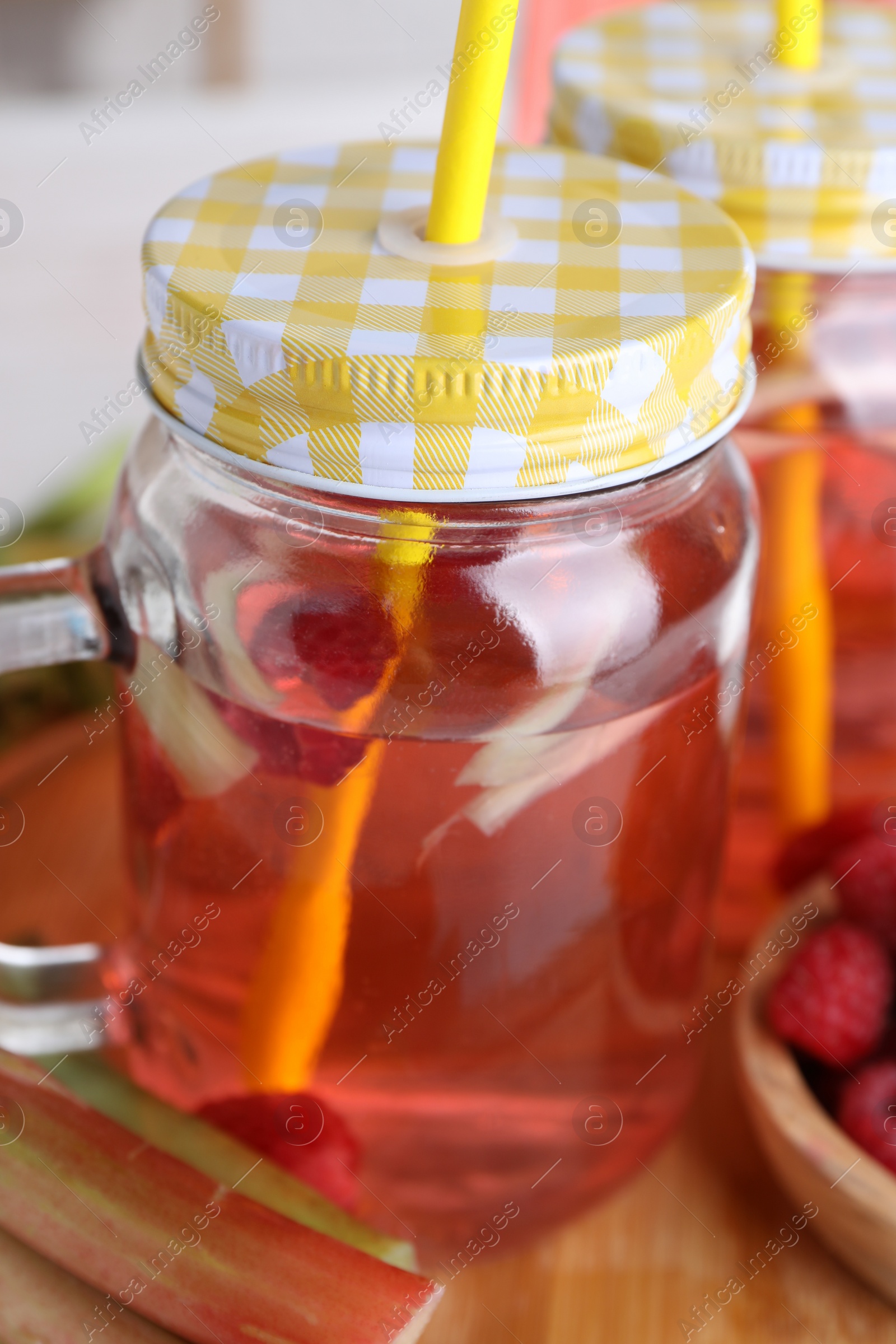 Photo of Mason jar of tasty rhubarb cocktail on wooden board, closeup