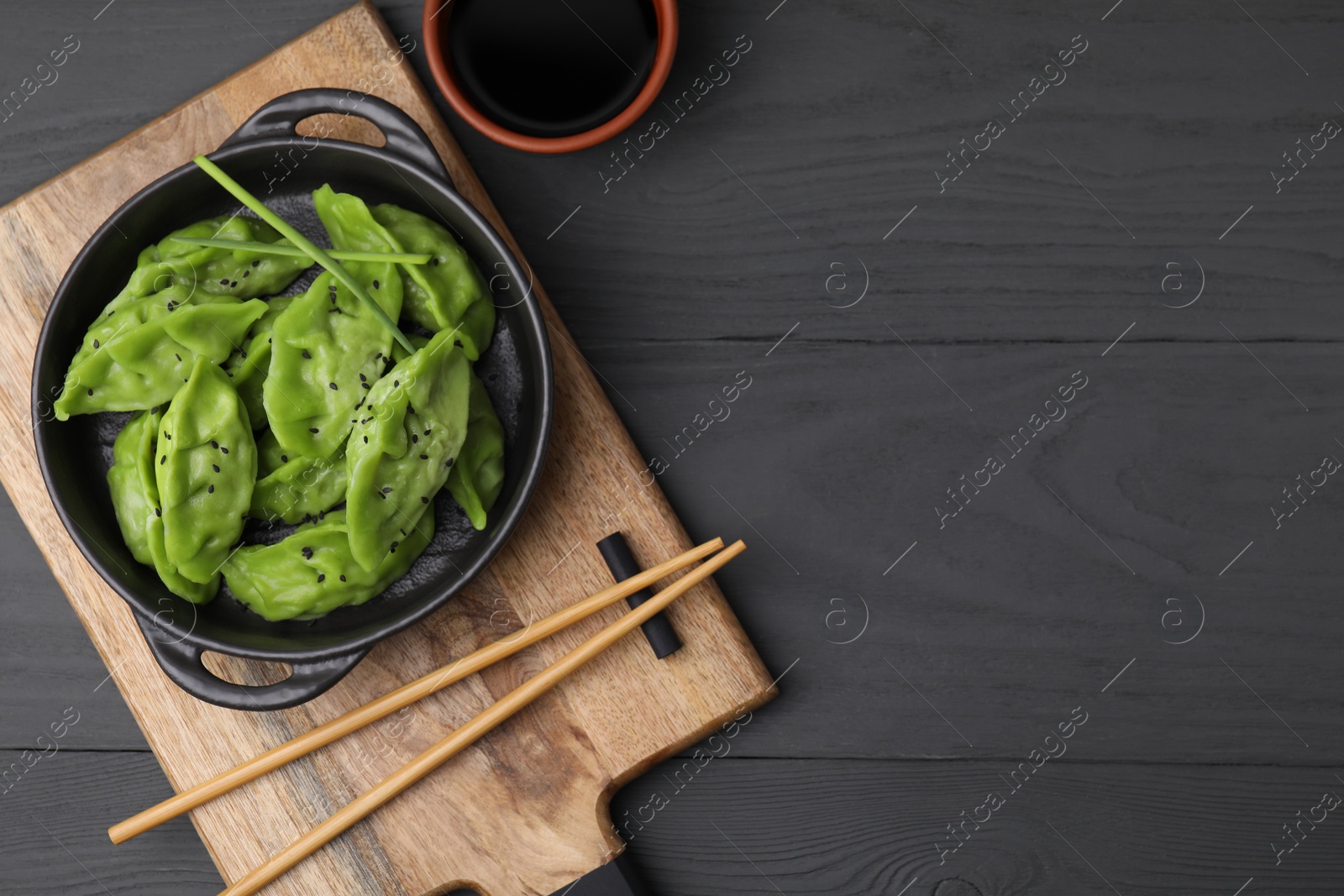 Photo of Delicious green dumplings (gyozas) served on grey wooden table, flat lay. Space for text