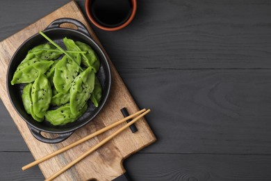 Photo of Delicious green dumplings (gyozas) served on grey wooden table, flat lay. Space for text