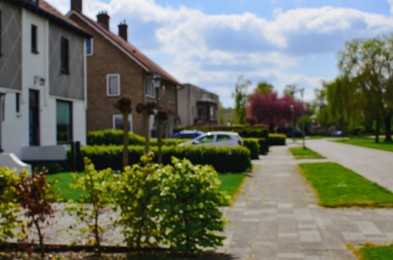 Blurred view of suburban street with beautiful houses and green shrubbery