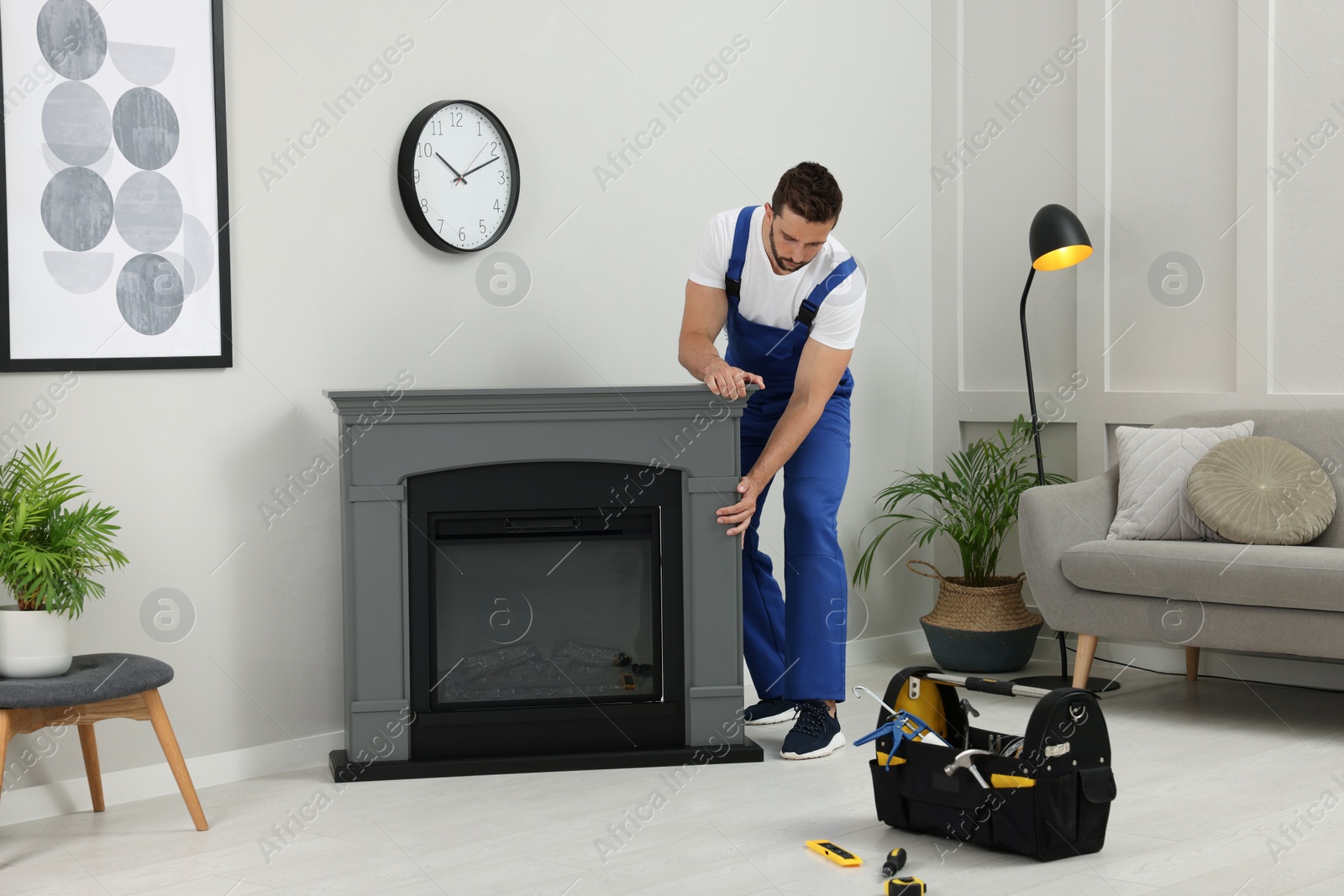 Photo of Professional technician installing electric fireplace in room