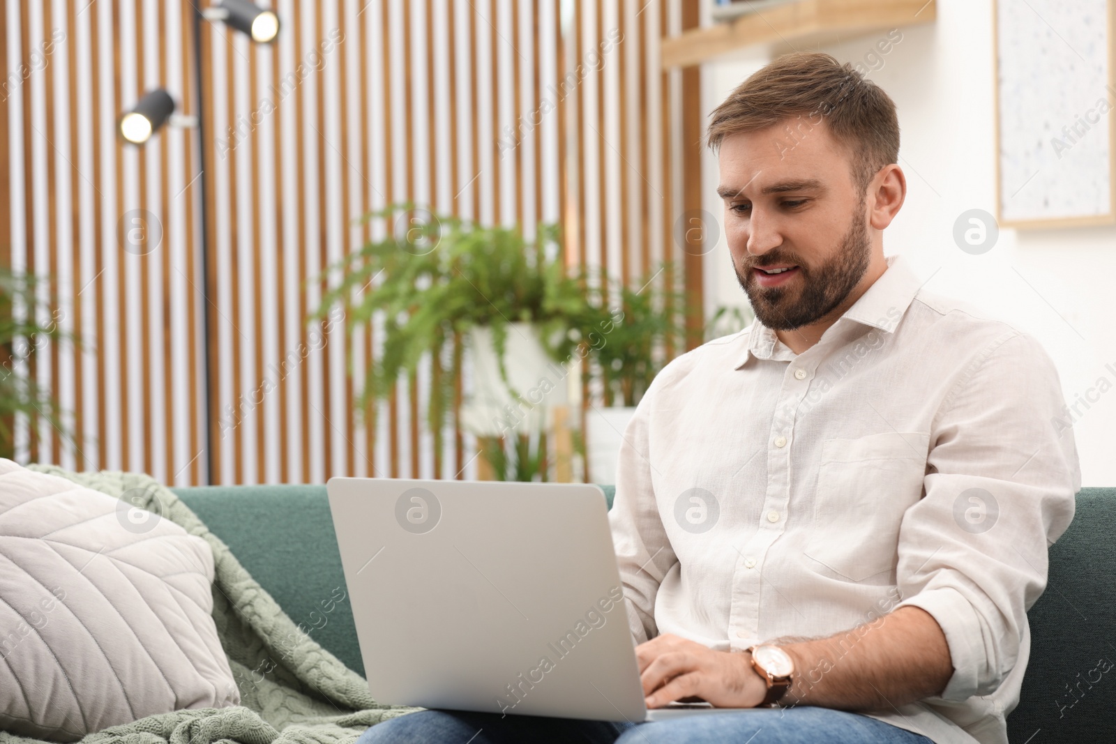 Photo of Young man working with laptop at home, space for text