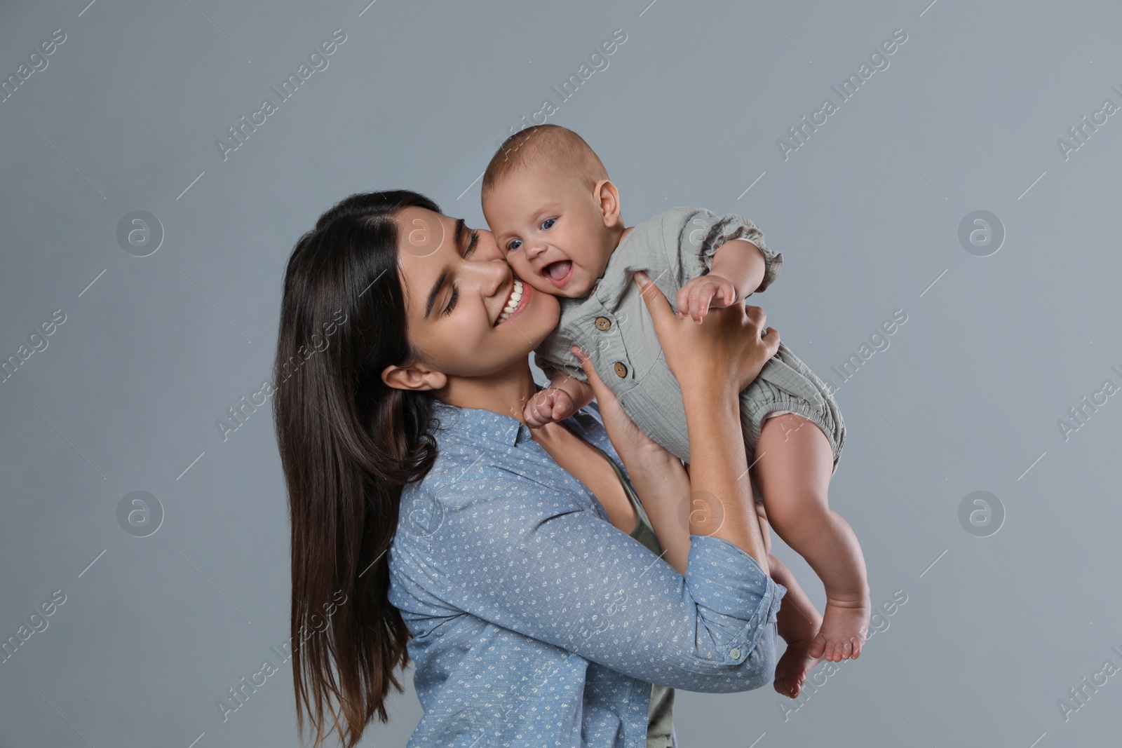 Photo of Beautiful mother with her cute baby on grey background