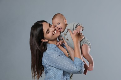 Beautiful mother with her cute baby on grey background