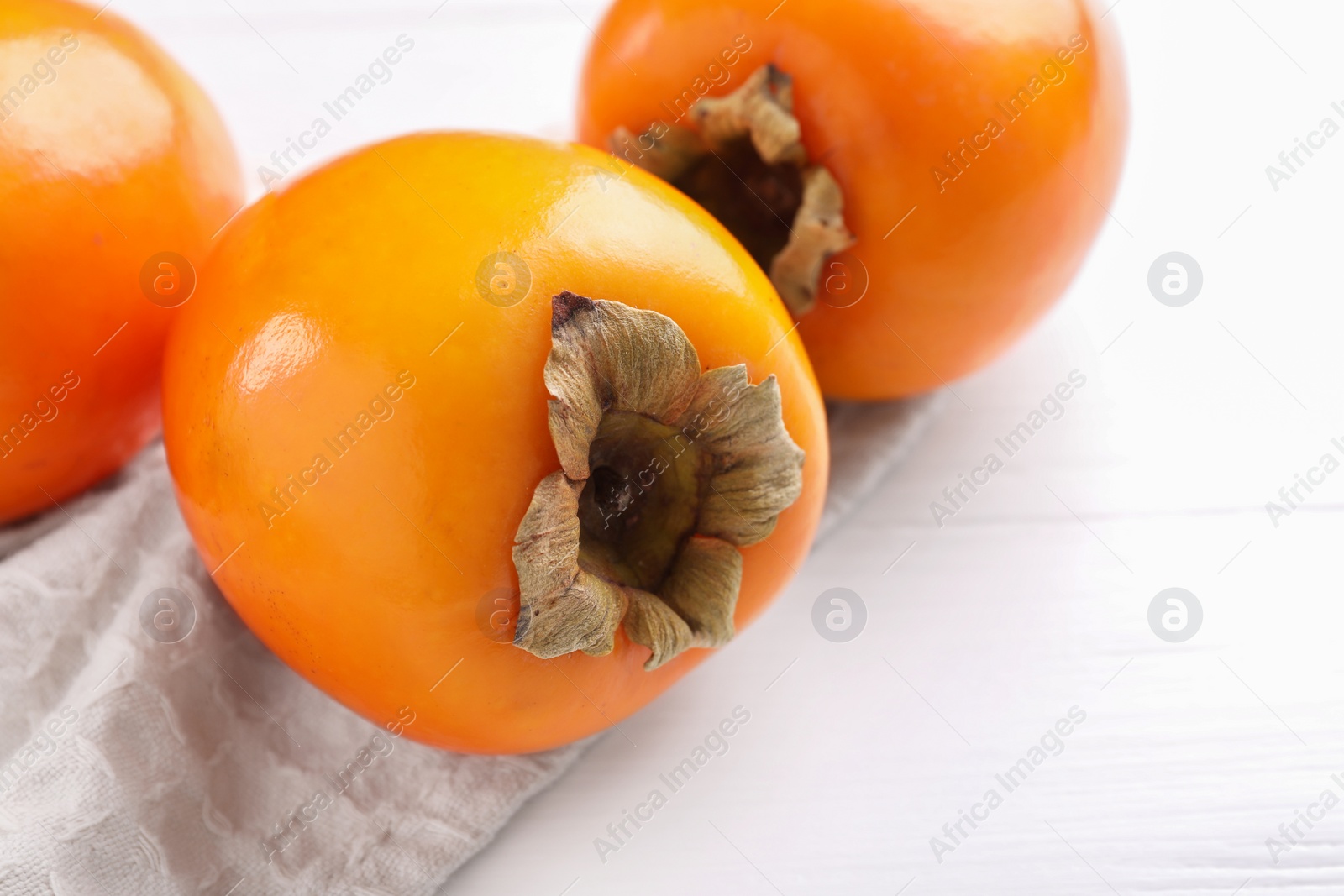 Photo of Delicious ripe persimmons on white wooden table, closeup