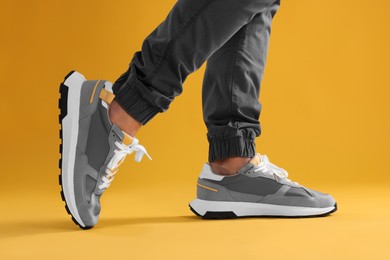 Photo of Man walking in sneakers on yellow background, closeup