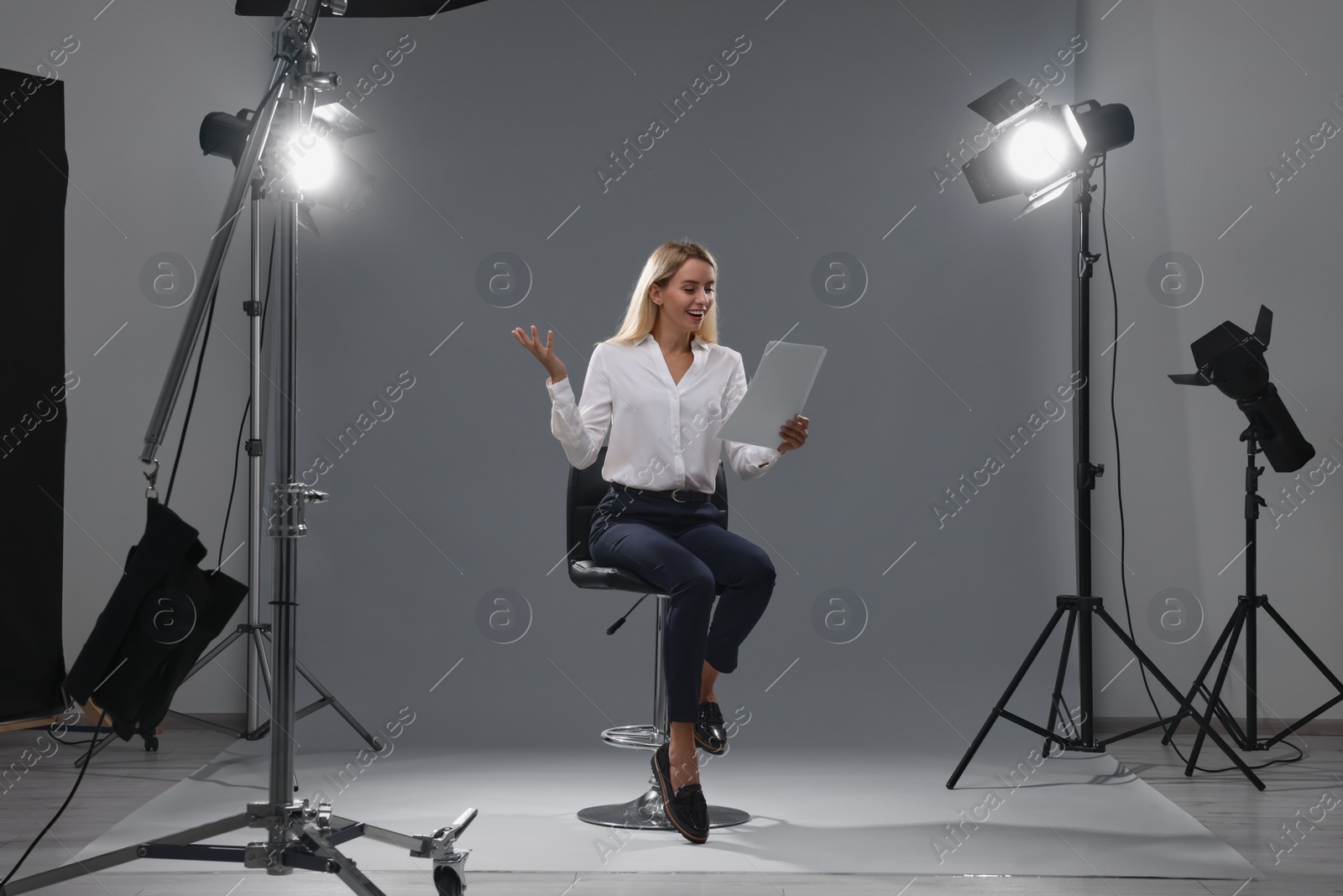 Photo of Casting call. Emotional woman with script performing against grey background in studio