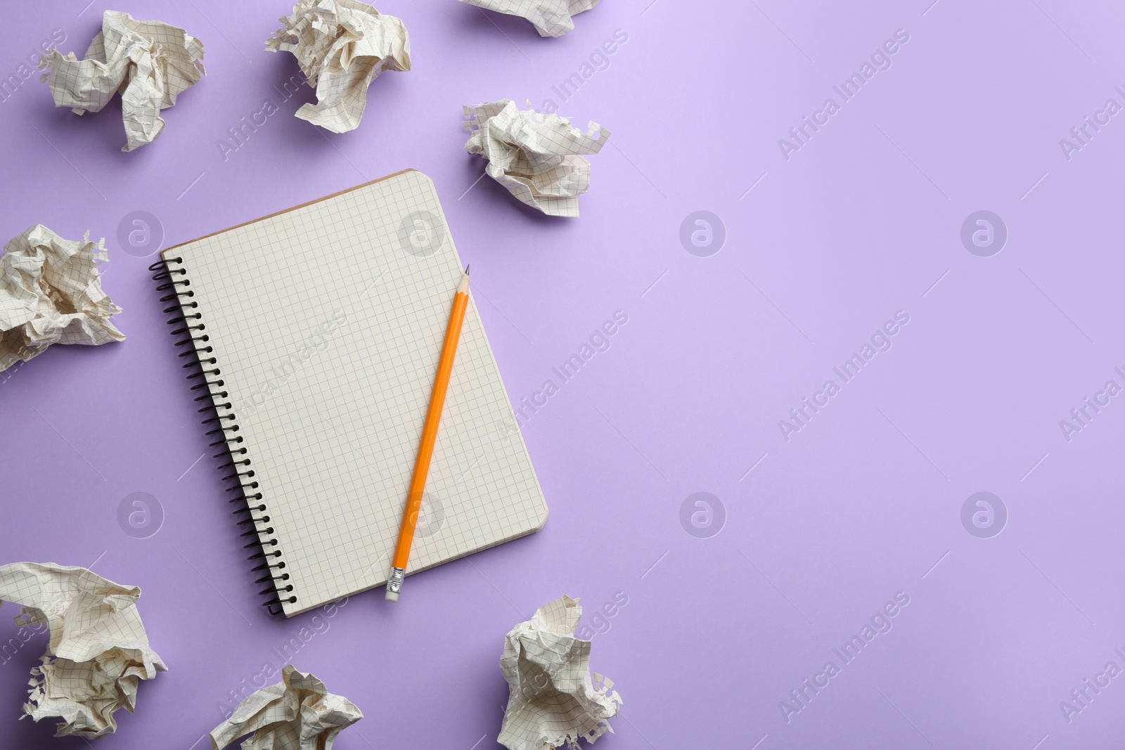 Photo of Notebook, pencil and crumpled sheets of paper on lilac background, flat lay. Space for text