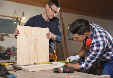 Photo of Professional carpenters working with wooden boards in workshop