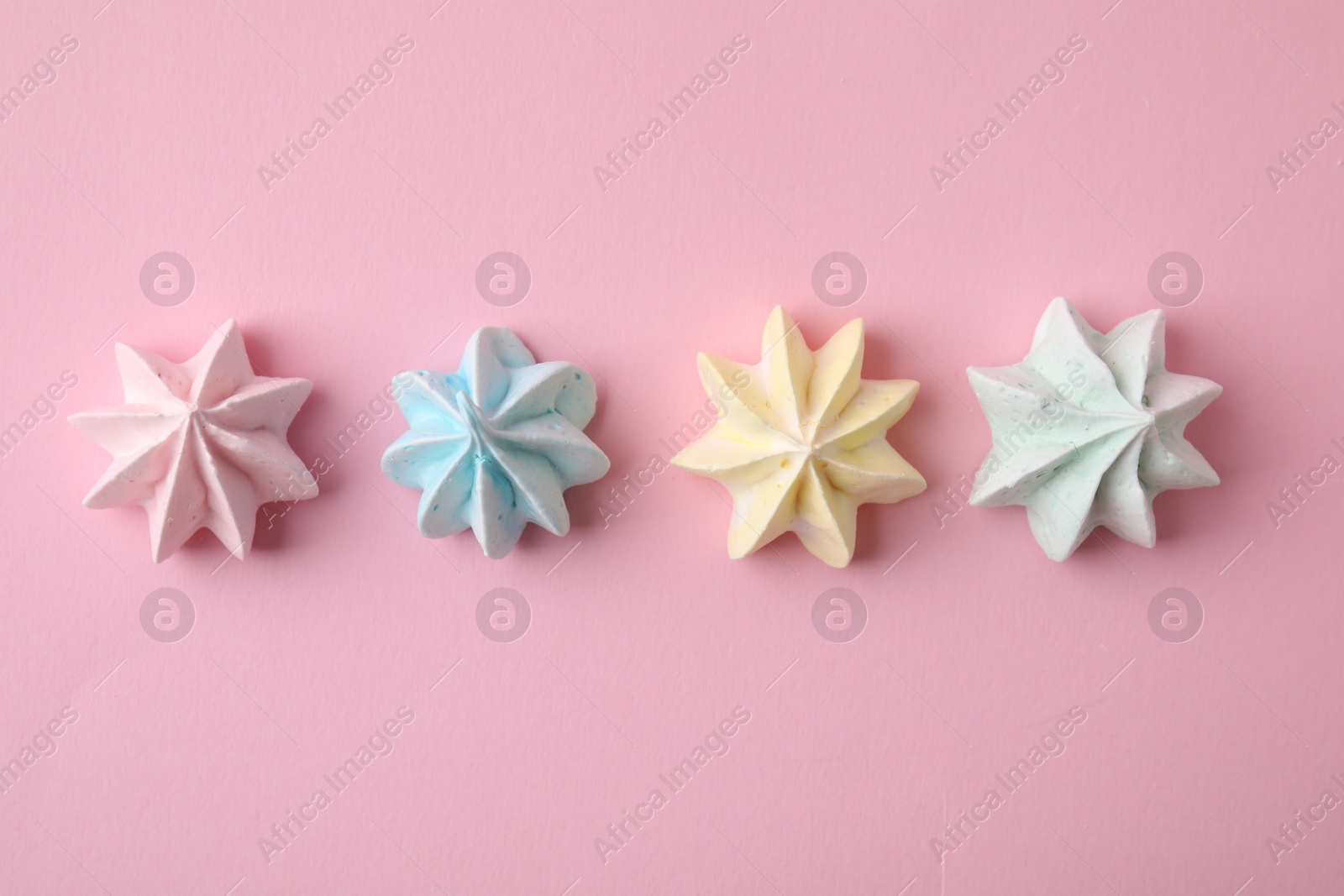 Photo of Many tasty meringue cookies on pink background, flat lay