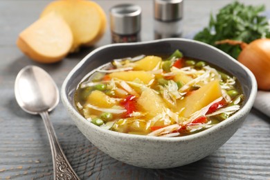 Photo of Bowl of delicious turnip soup on grey wooden table, closeup