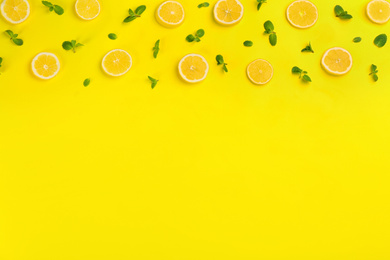 Lemonade layout with juicy lemon slices and mint on yellow background, top view. Space for text