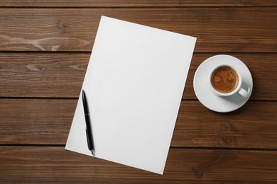 Photo of Blank paper sheet, pen and cup of coffee on wooden table, flat lay. Space for text