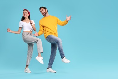 Photo of Happy couple dancing together on light blue background, space for text