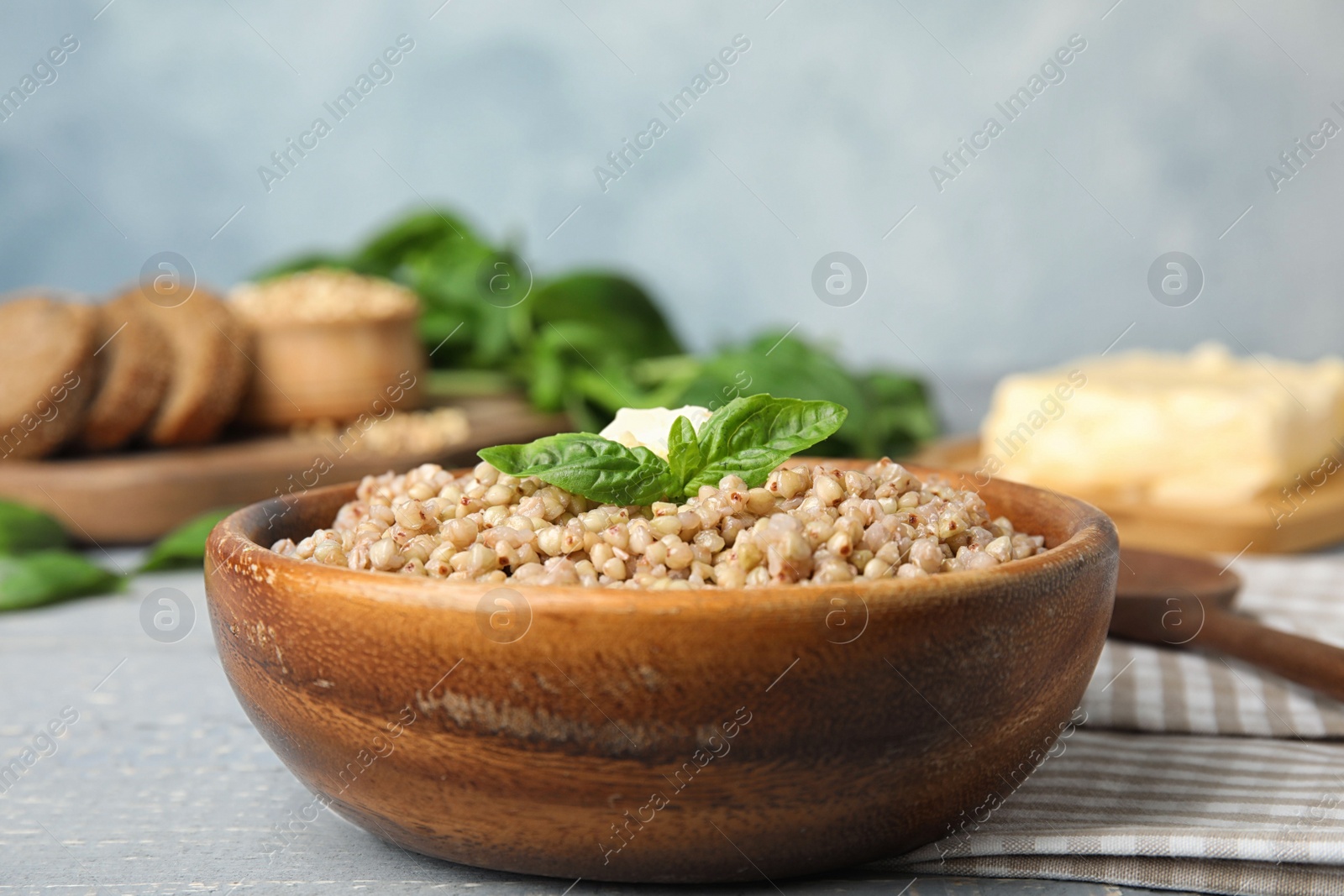 Photo of Tasty buckwheat porridge with butter on grey wooden table