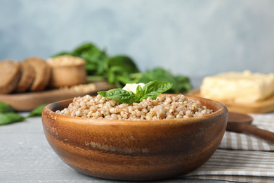 Photo of Tasty buckwheat porridge with butter on grey wooden table