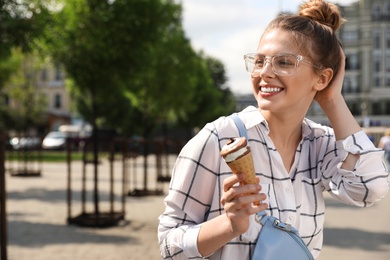 Young happy woman with ice cream cone on city street. Space for text