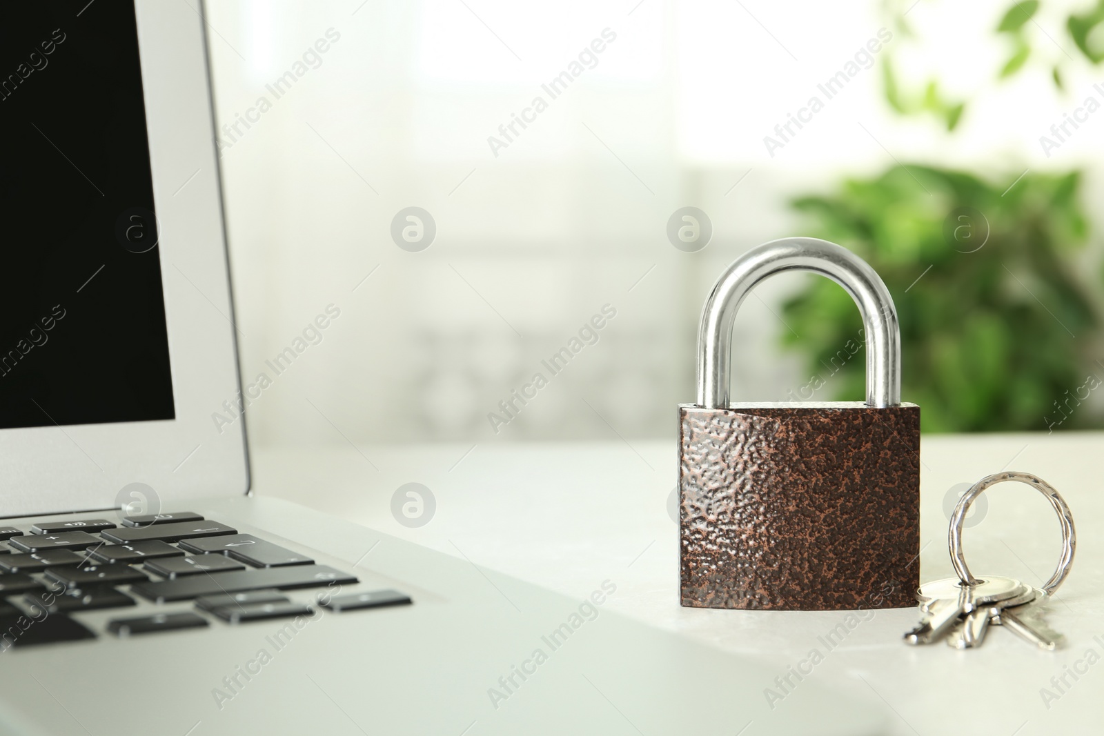 Photo of Metal lock, keys and laptop on table, closeup. Protection from cyber attack