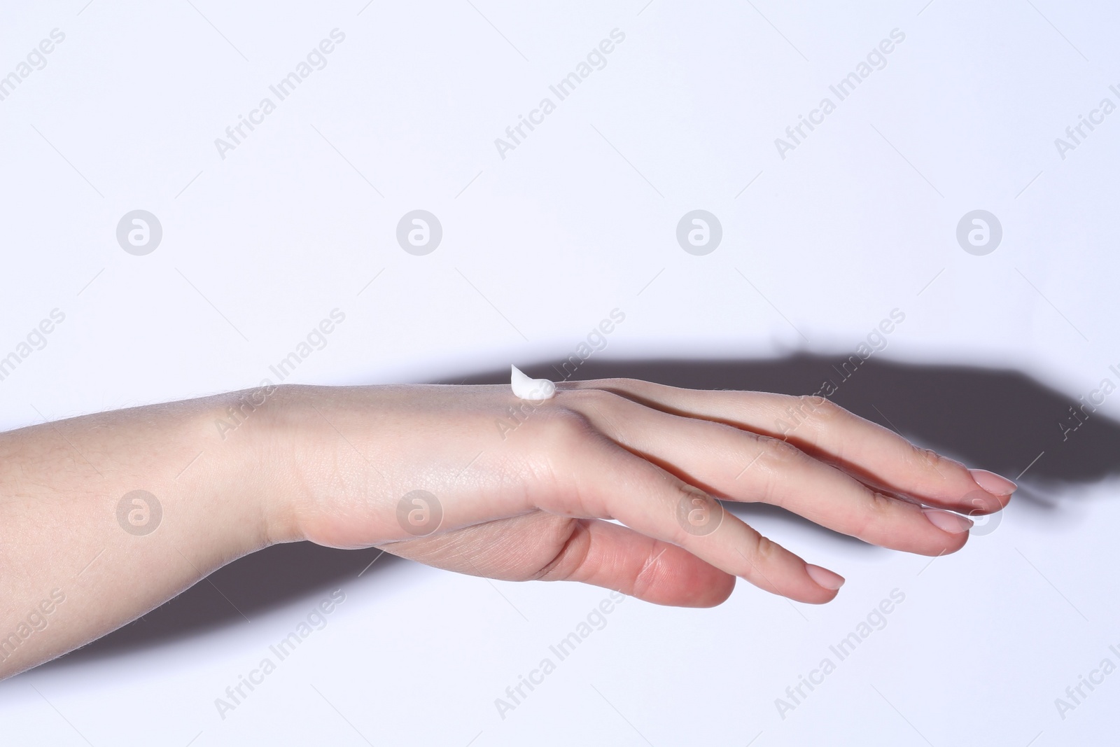 Photo of Woman with cream on her hand against white background, closeup