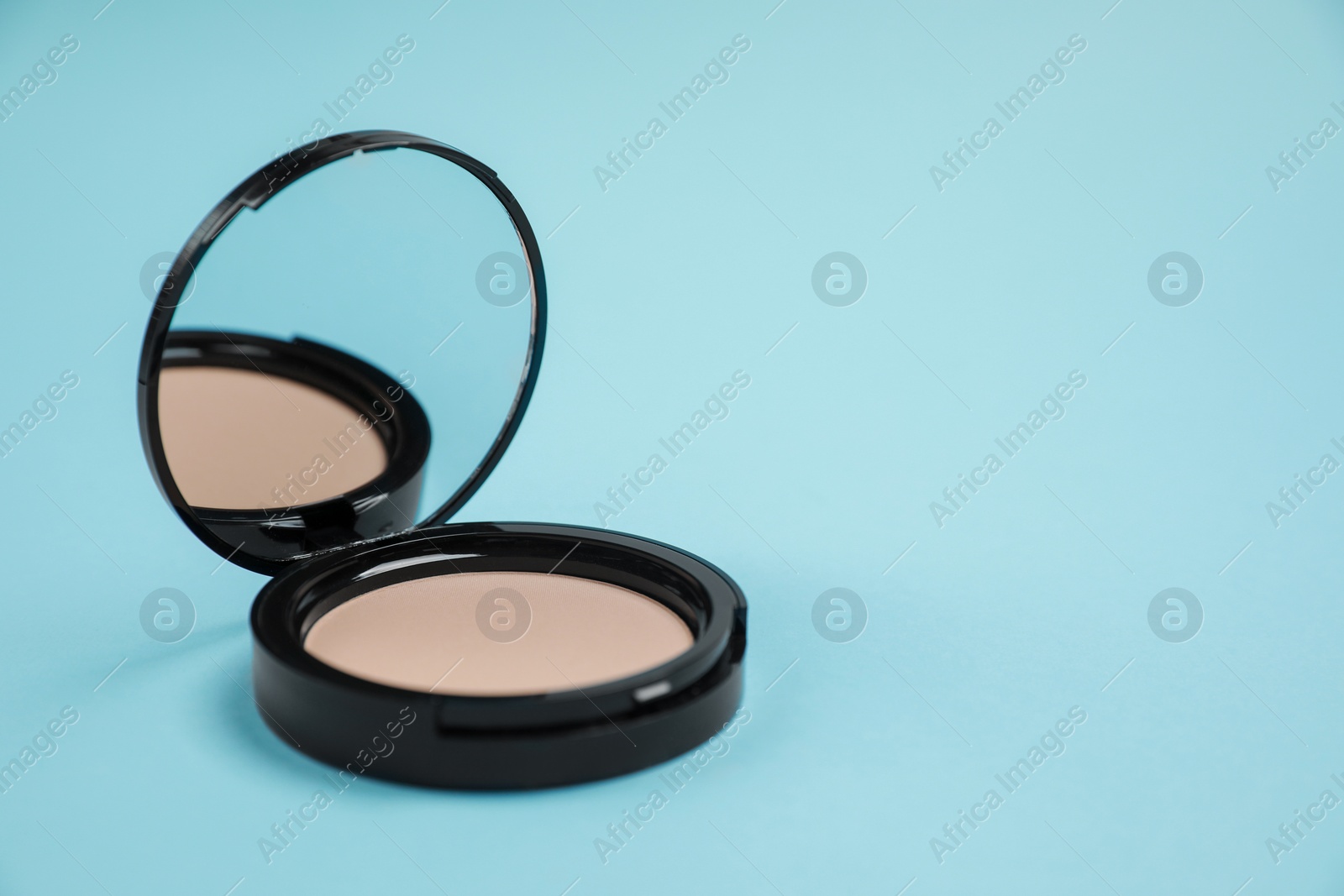 Photo of One face powder on light blue background, space for text