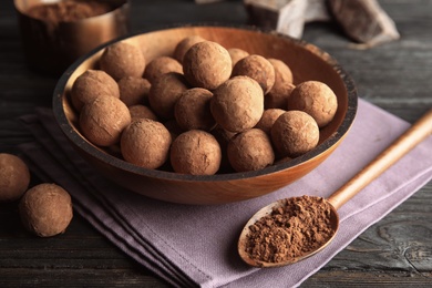 Photo of Plate with chocolate truffles on wooden background