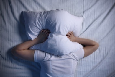 Young woman suffering from insomnia in bed, top view