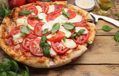 Photo of Delicious Caprese pizza with tomatoes, mozzarella and basil served on wooden table