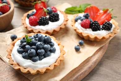 Different berry tarts on wooden table. Delicious pastries