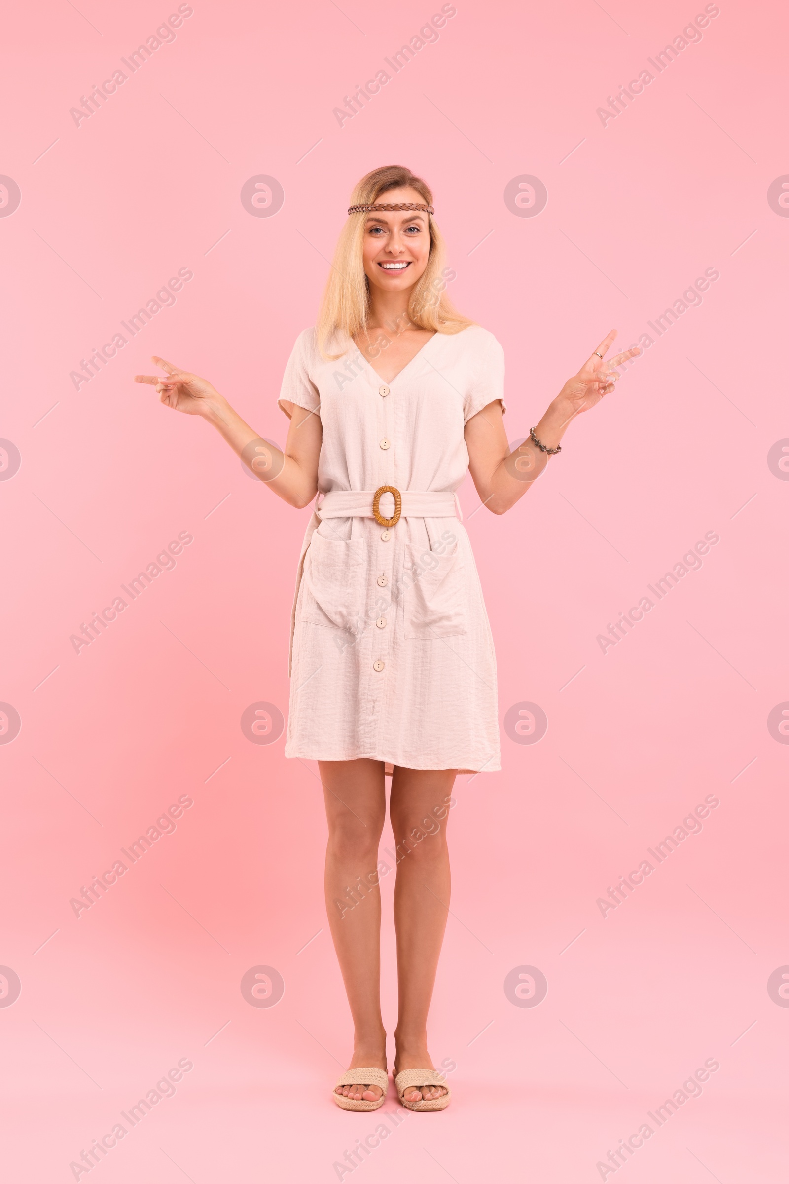 Photo of Beautiful hippie woman showing peace signs on pink background