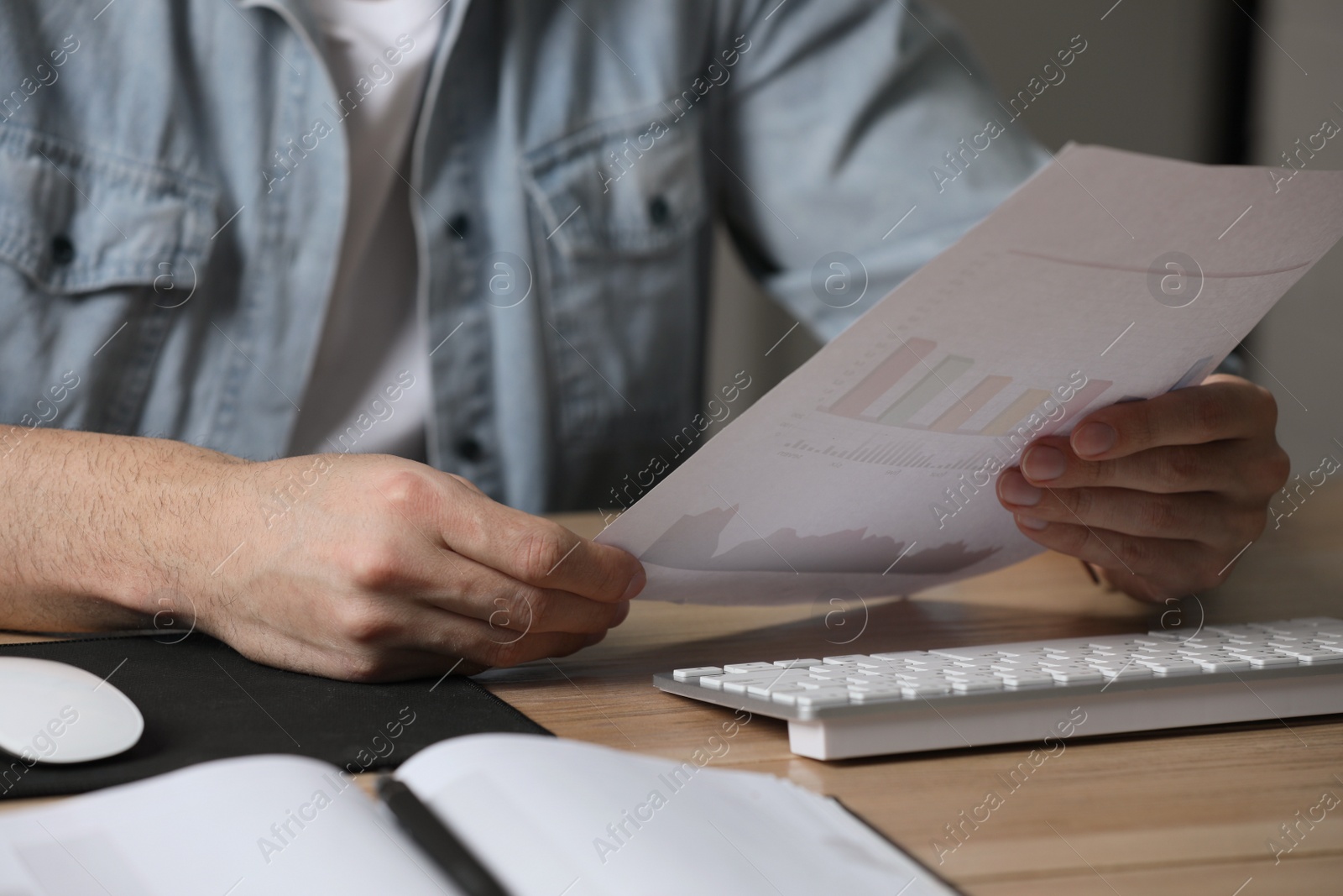 Photo of Man working with document at table in office, closeup